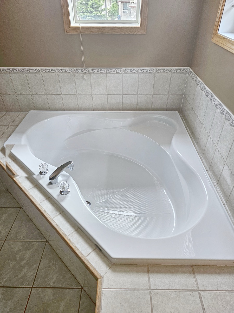 Corner soaker tub polished to a shine with clean tile surround after a NeatNow first time clean in Calgary