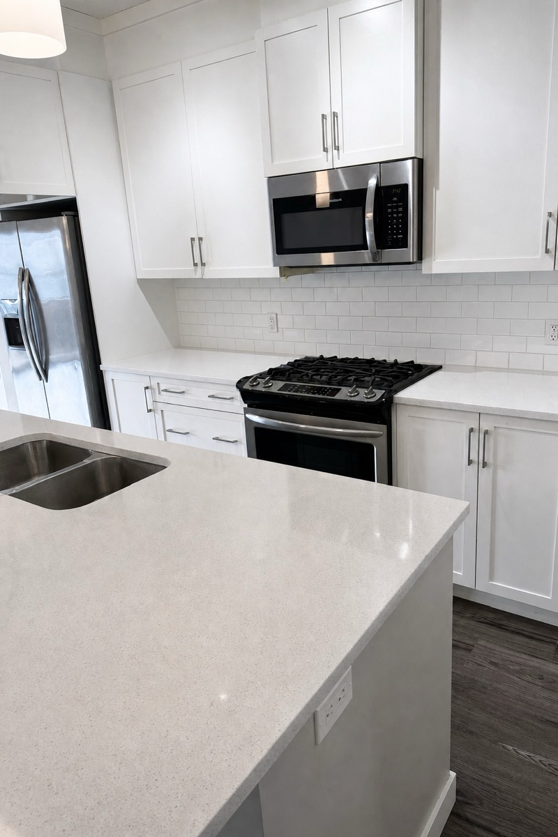 White kitchen with polished quartz counters, spotless stovetop, and gleaming appliance exteriors after a NeatNow first time clean in Calgary